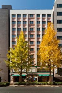 dos árboles con hojas amarillas delante de un edificio en Kadoya Hotel, en Tokio