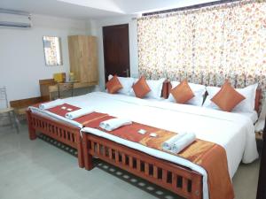 1 dormitorio con 1 cama grande con sábanas blancas y almohadas de color naranja en A V Residency, en Kochi