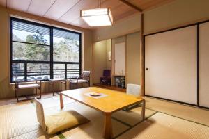 een kamer met een tafel en stoelen en een groot raam bij Hotel Seikoen in Nikko
