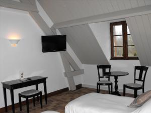 a bedroom with a bed and a table and chairs at L'Orée des Chênes, The Originals Relais (Relais du Silence) in La Ferté-Saint-Aubin