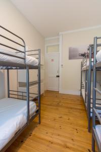 Change The World Hostels - Cascais - Estoril في مونتي استوريل: غرفة بها ثلاثة أسرة بطابقين وأرضية خشبية