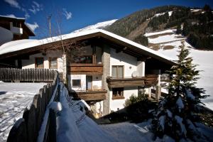a house in the snow with a fence at Edelberg Apartments in Außervillgraten