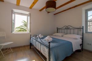 a bedroom with a bed with a blue blanket and two windows at Bargujac Summer House in Vis