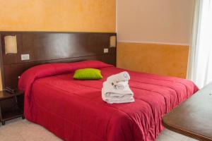 a bedroom with a red bed with towels on it at Hotel Okinawa in Rimini