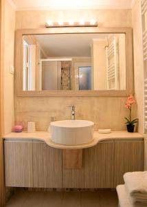 een badkamer met een wastafel en een grote spiegel bij Meros - Athenian Residencies in Athene