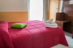 a bedroom with a pink bed with a green pillow at Hotel Okinawa in Rimini