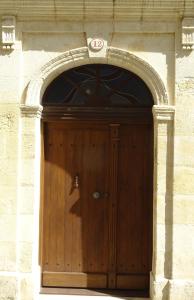 a wooden door in a stone building with an arch at 12 Rue des Ecoles in Saint-Émilion