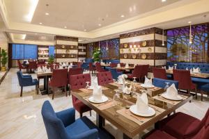 a restaurant with wooden tables and blue chairs at Konoz Al Yam Hotel Jeddah in Jeddah