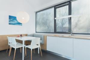 eine Küche mit einem weißen Tisch, Stühlen und Fenstern in der Unterkunft Apartamenty Laguna Boulevard by Renters Prestige in Ustronie Morskie