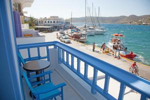 een balkon met een blauwe stoel en boten in het water bij Saint George Valsamitis Superior in Katápola