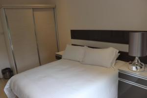um quarto com uma grande cama branca e um candeeiro em AMB Apartments em Lusaka