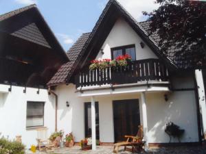 ein weißes Haus mit einem Balkon mit Blumen darauf in der Unterkunft Haus Kollwitzweg - Ferienwohnungen in Goslar