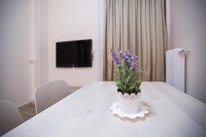 a white table with a vase with purple flowers on it at Paradise Apartment in Peiraiki in Piraeus