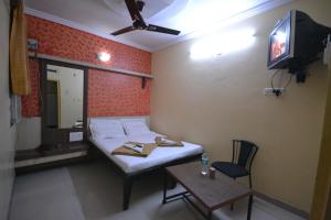 a small room with a bed and a table and a tv at Hotel Madhava in Shirdi
