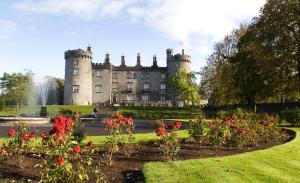 an old castle with red flowers in front of it at Kilkenny Inn in Kilkenny