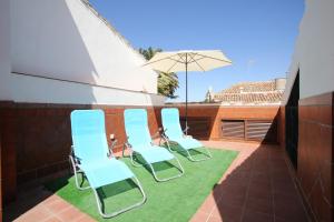 eine Gruppe Stühle und ein Sonnenschirm auf einer Terrasse in der Unterkunft Holiday House Tenorio in Ronda