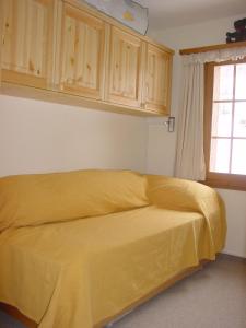 a yellow bed in a room with a window at bel-air 21 u.23 in Bellwald