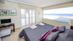 Schlafzimmer mit einem Bett mit lila Kissen und einem TV in der Unterkunft Luxury Bay View Villa 28 Right On The Beach in Protaras