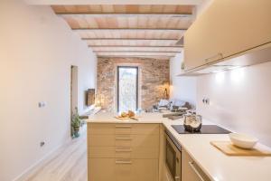 a kitchen with white counters and a brick wall at Flateli- Plaça Catalunya 2-1 in Girona