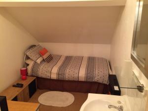 a small bedroom with a bed and a sink at Melrose Guest House in Whitley Bay