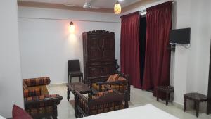 ein Wohnzimmer mit Stühlen, einem TV und roten Vorhängen in der Unterkunft Hotel Murud Marina in Murud
