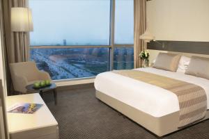 um quarto de hotel com uma cama e uma grande janela em Erbil Arjaan by Rotana em Arbil