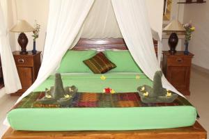 a bedroom with a green bed with two birds on it at Villa Bungsil Gading in Ubud