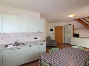 uma cozinha com armários brancos e uma mesa com um lavatório em Belvilla by OYO Fior di melo em Caldes