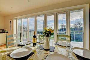 a dining room with a table with a vase of flowers at Awelfryn in Pwllheli