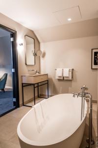 een badkamer met een ligbad en een wastafel bij Pillows Grand Boutique Hotel Ter Borch Zwolle in Zwolle