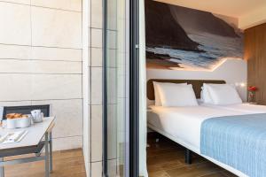 um quarto com uma cama, uma secretária e uma mesa com um computador portátil em Eurostars Cascais em Cascais