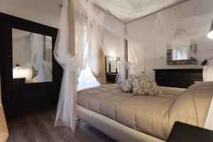 a bedroom with a bed with white curtains and a mirror at Your Apartment in Il-Furjana