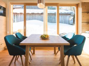 a dining room with a wooden table and blue chairs at Chavida Chalets in Schattwald