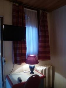 ルーアンにあるHotel Beausejourの窓付きの部屋のテーブル上のランプ