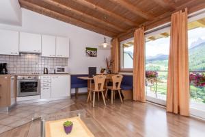 a kitchen with a table and chairs and a large window at Appartements Sonneck in Funes