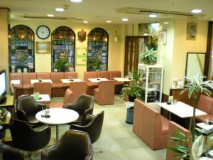 een restaurant met tafels en stoelen en een klok aan de muur bij Green Hill Hotel Tennoji Ekimae in Osaka