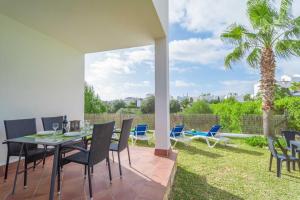 a patio with a table and chairs and a palm tree at Marina D'Or IV Casa 5 in Cala d´Or