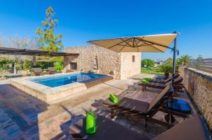 a patio with a pool and an umbrella and chairs at Na Molla in Manacor