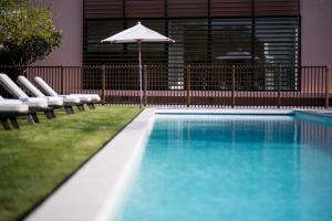 een zwembad met stoelen en een parasol bij Château Cordeillan-Bages in Pauillac