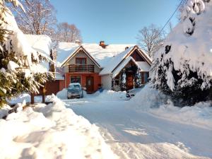 a house covered in snow with a car parked in the driveway at Rodzinny Domek Apartament in Wisłoczek