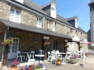 un restaurante con sillas y mesas blancas frente a un edificio en Hotel Du Tertre, en Mont-Dol