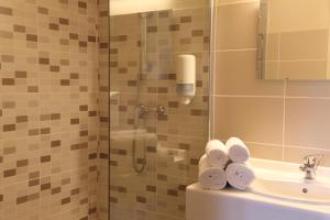 łazienka z prysznicem, umywalką i ręcznikami w obiekcie Hotel Restaurant L'Espassole w mieście Thuir