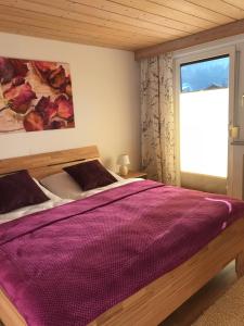 1 dormitorio con 1 cama con edredón morado en Haus Glätzle en Breitenwang