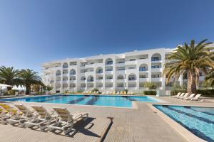 a hotel with a swimming pool and chairs and a building at Ukino Terrace Algarve Concept in Armação de Pêra