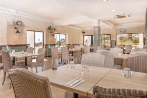 a restaurant with tables and chairs and windows at Ukino Terrace Algarve Concept in Armação de Pêra