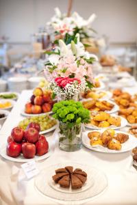 een lange tafel met borden met voedsel en bloemen bij Hotel Doge in Milano Marittima