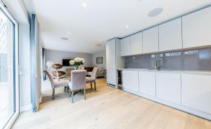 a kitchen and dining room with white cabinets and a table at Lux St James Park Apartment Central London FREE WIFI by City Stay Aparts London in London