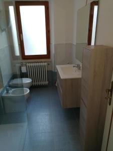 uma casa de banho com um lavatório, um WC e uma janela. em B&B A Ridosso em Gubbio