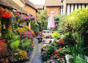 a garden with a patio with an umbrella and flowers at Bournville House & Cafe in Birmingham