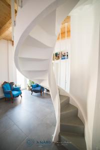 a white spiral staircase in a living room with blue chairs at Bed & breakfast La Nassa in Taranto